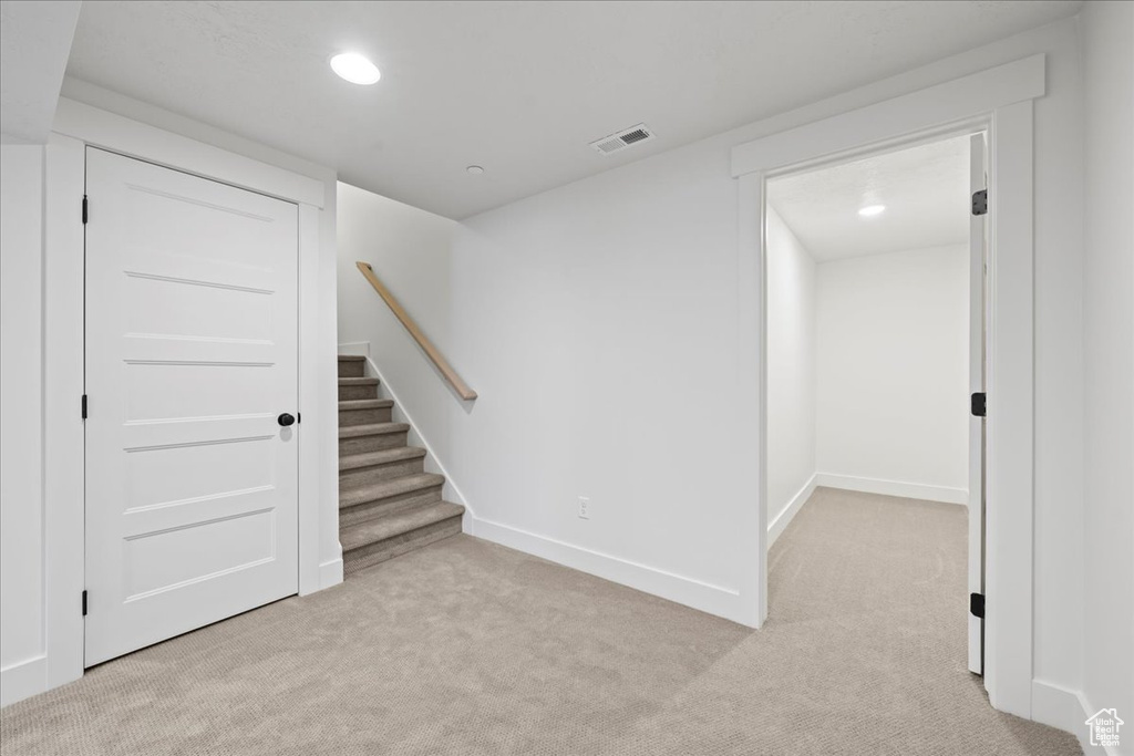 Unfurnished room featuring light carpet, recessed lighting, and stairway