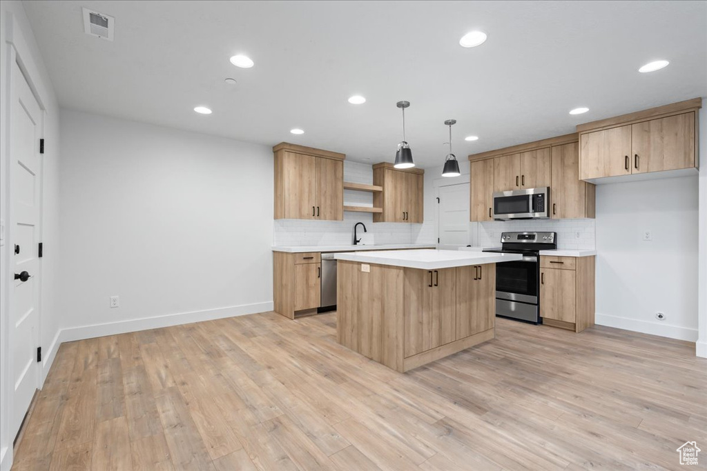 Kitchen with stainless steel appliances, open shelves, light countertops, backsplash, and a kitchen island