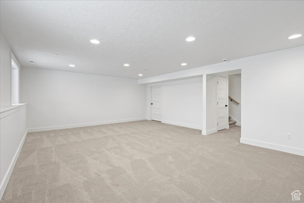 Finished below grade area with recessed lighting, light carpet, and stairway