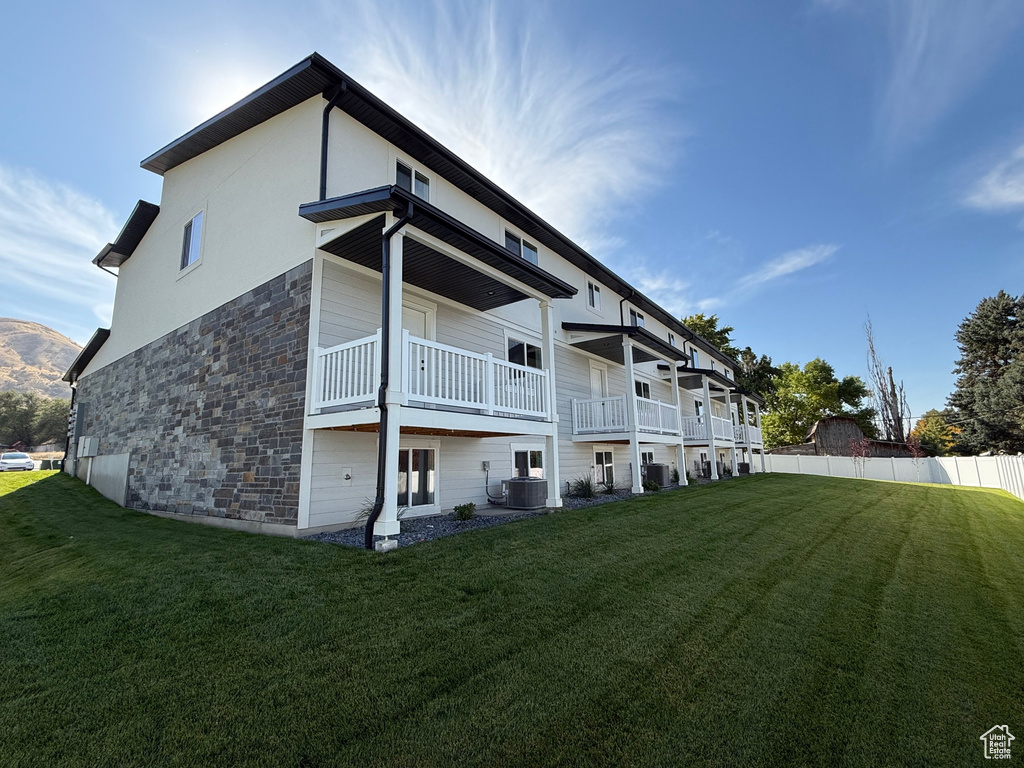 Back of property with stone siding, a balcony, and stucco siding