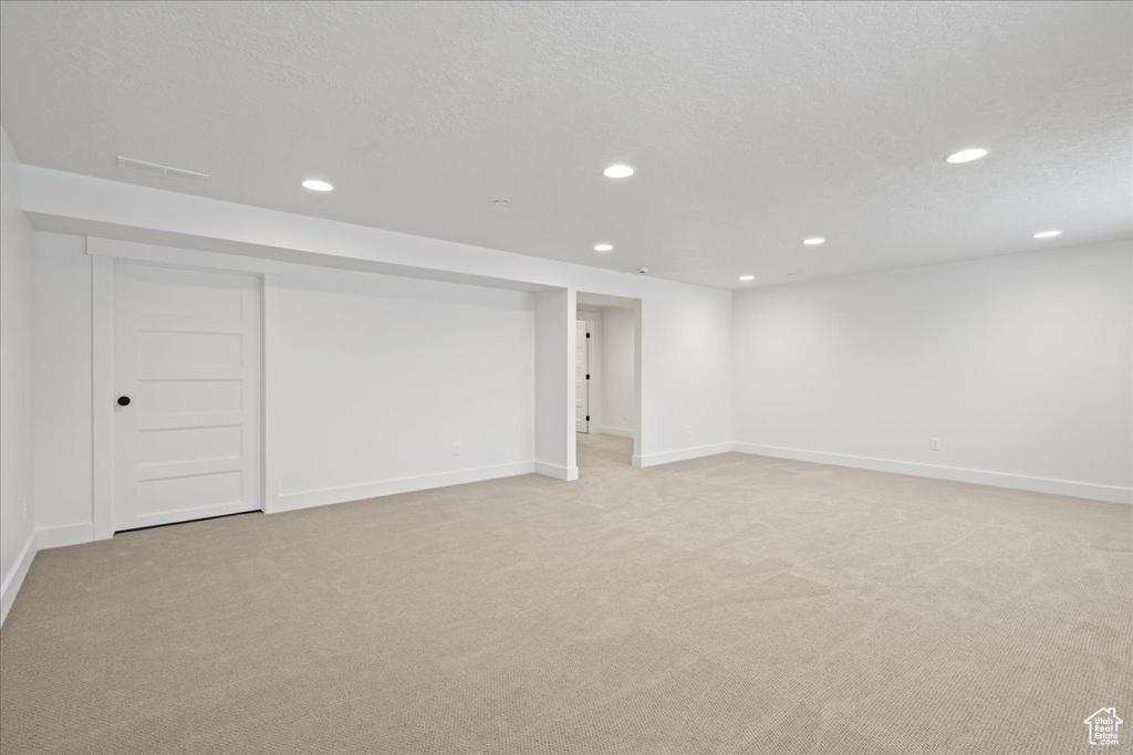 Finished below grade area with light colored carpet and recessed lighting