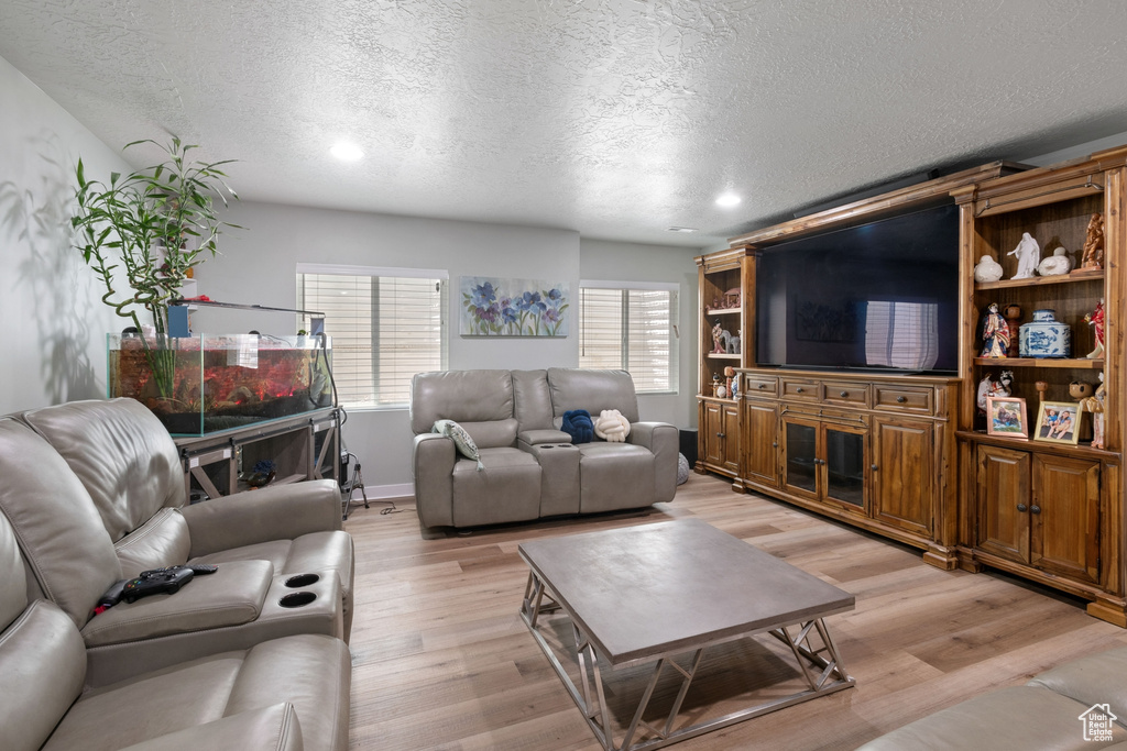 Living area featuring a textured ceiling, light wood-style flooring, and recessed lighting