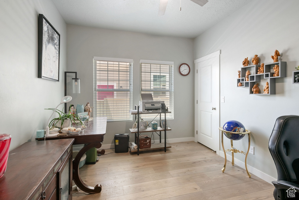 Home office featuring light wood-type flooring and a ceiling fan