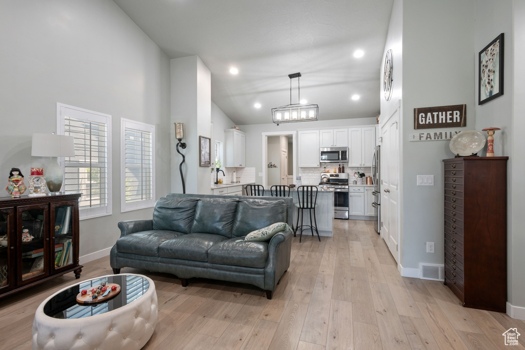 Living room with lofted ceiling, light wood-type flooring, and recessed lighting