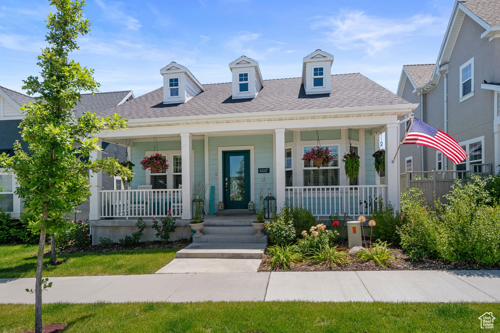 View of front of house featuring covered porch and a shingled roof