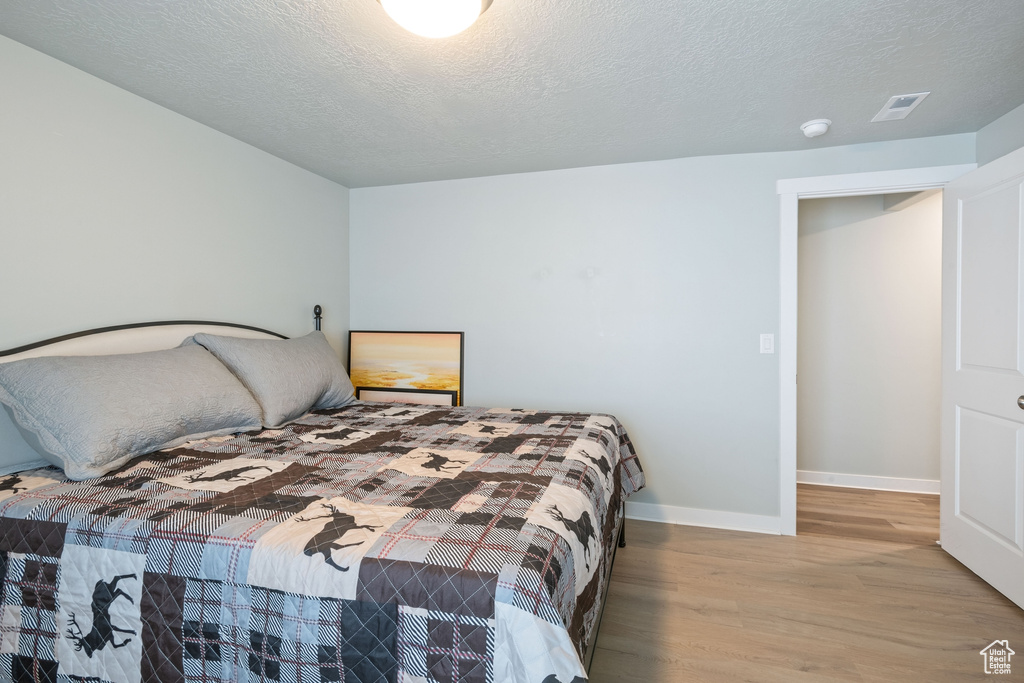 Bedroom featuring wood finished floors and a textured ceiling