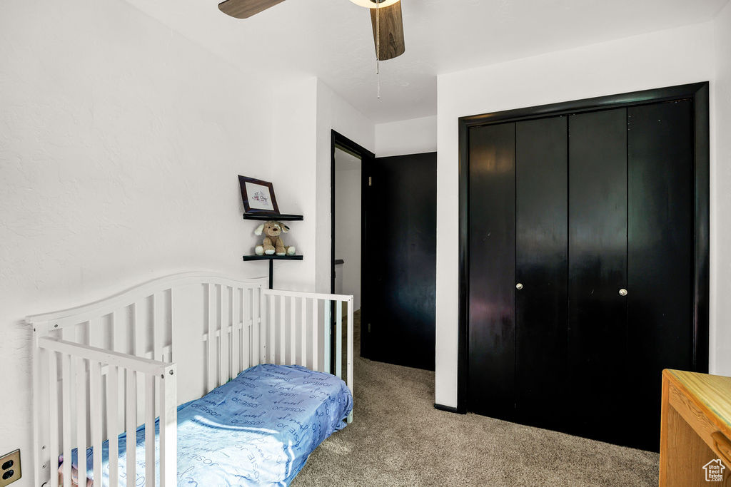Carpeted bedroom with a closet and a ceiling fan
