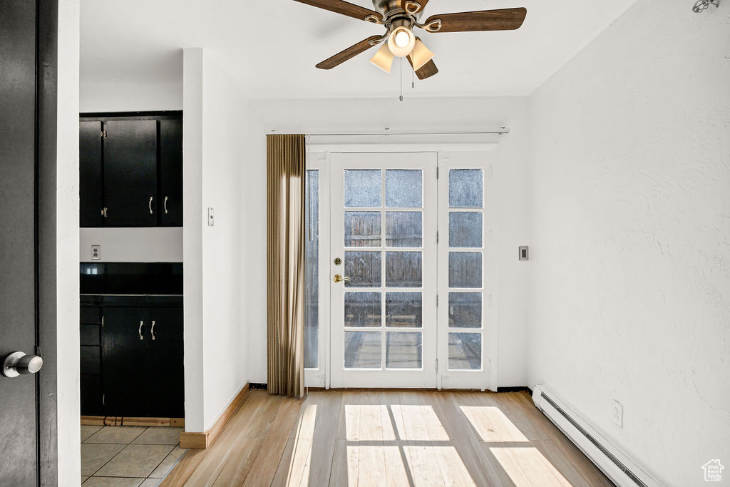 Doorway featuring a baseboard radiator, a ceiling fan, and wood finished floors