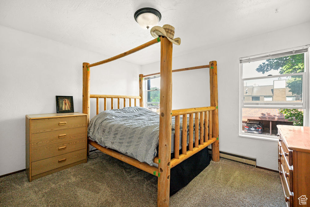 Carpeted bedroom featuring a baseboard heating unit and baseboards