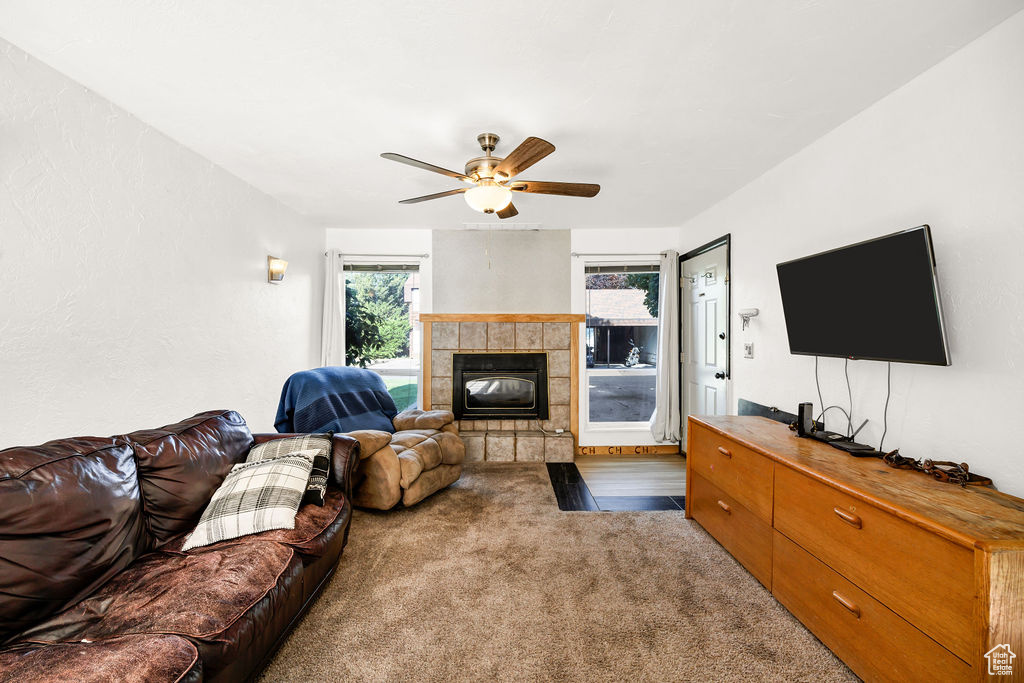 Living area with carpet floors, a tiled fireplace, and ceiling fan