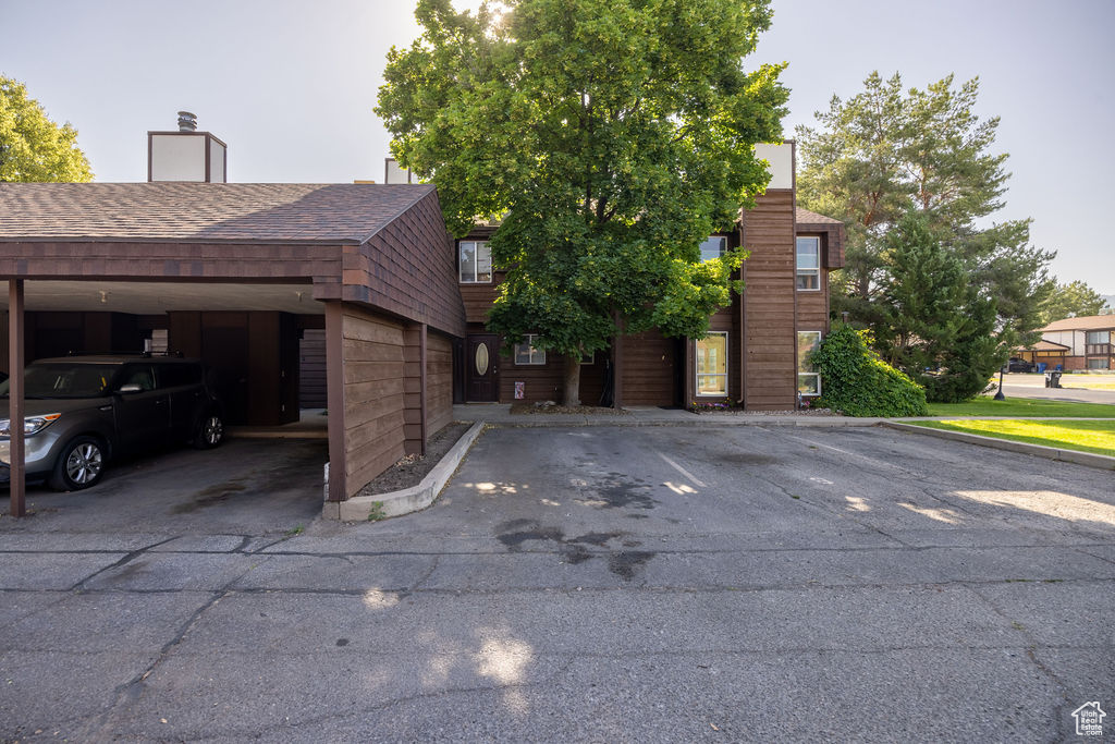 View of front of home with uncovered parking and roof with shingles