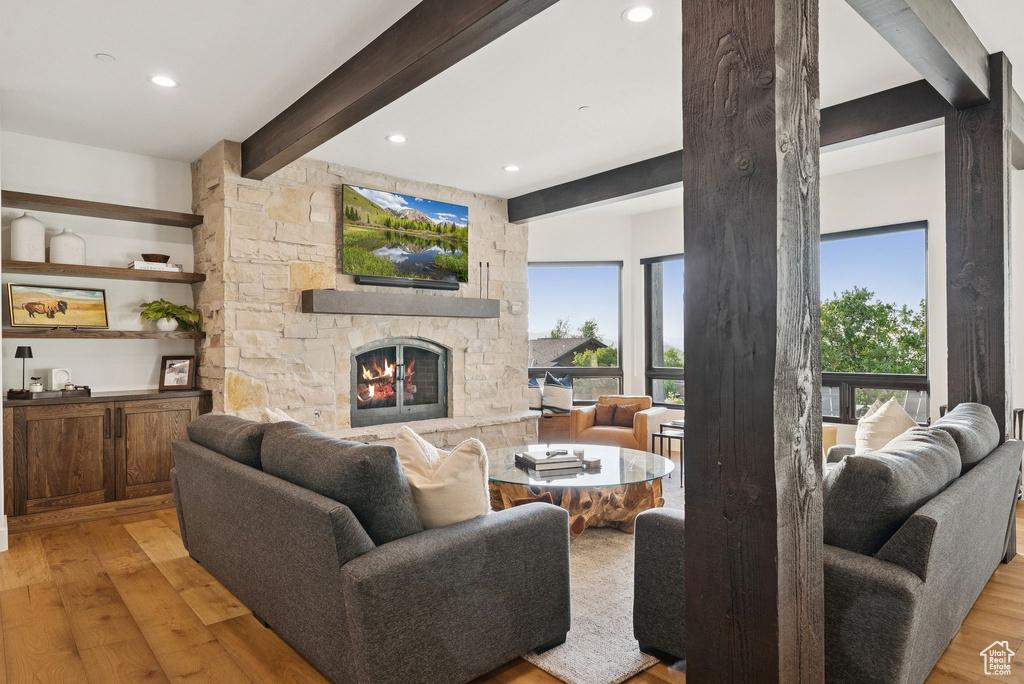 Living room with light wood-style floors, beam ceiling, a fireplace, and recessed lighting