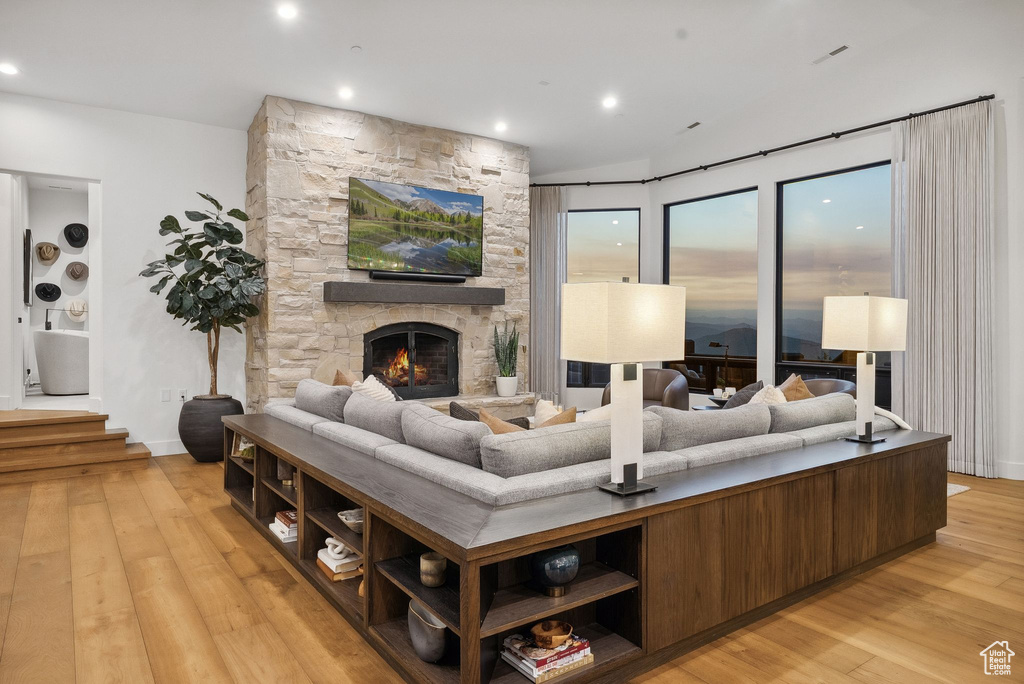 Living area featuring light wood finished floors, a stone fireplace, and recessed lighting