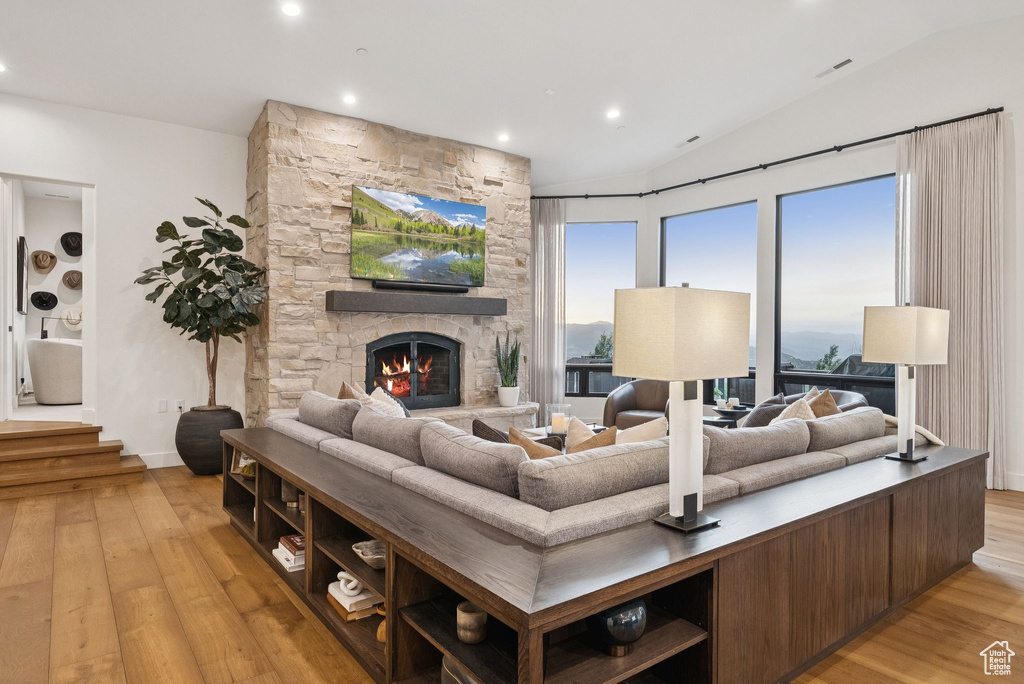 Living area with light wood-type flooring, lofted ceiling, recessed lighting, and a fireplace