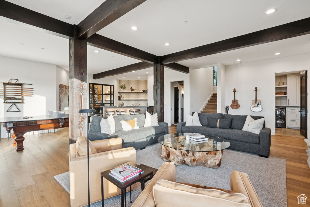 Living area featuring washer / dryer, beam ceiling, wood finished floors, recessed lighting, and stairway