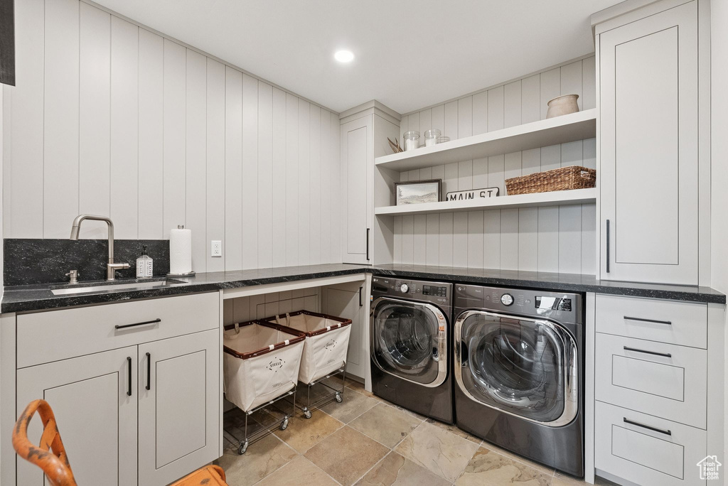 Laundry area featuring washer and dryer, cabinet space, wooden walls, and light stone finish floors
