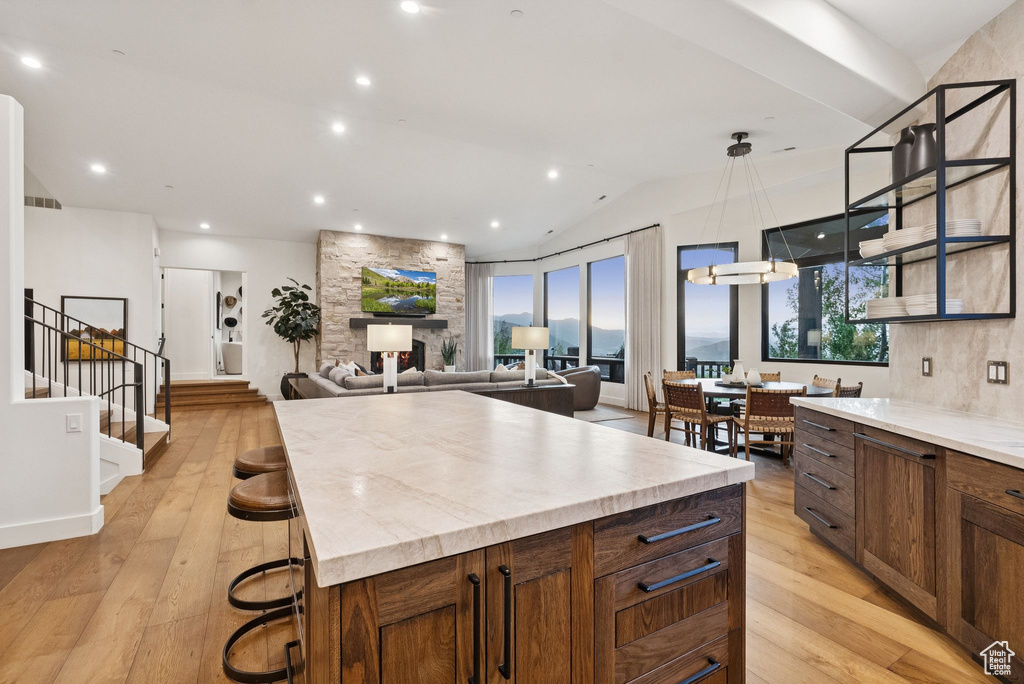 Kitchen with light wood-style floors, light countertops, a center island, lofted ceiling, and decorative light fixtures