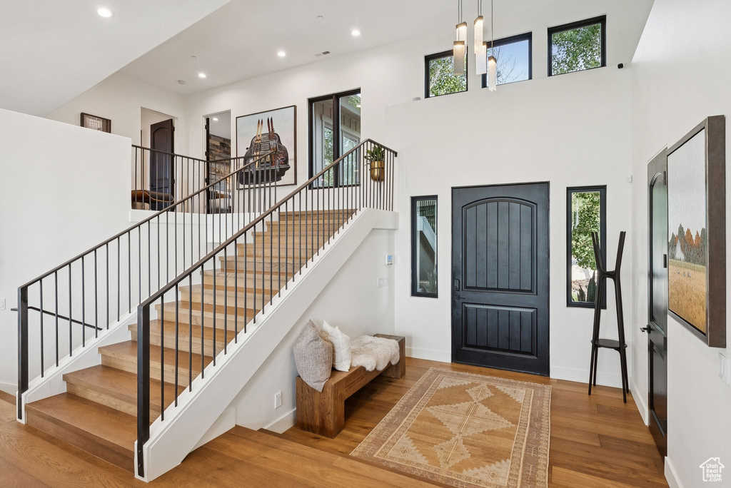 Entryway featuring wood finished floors, healthy amount of natural light, a towering ceiling, recessed lighting, and stairs