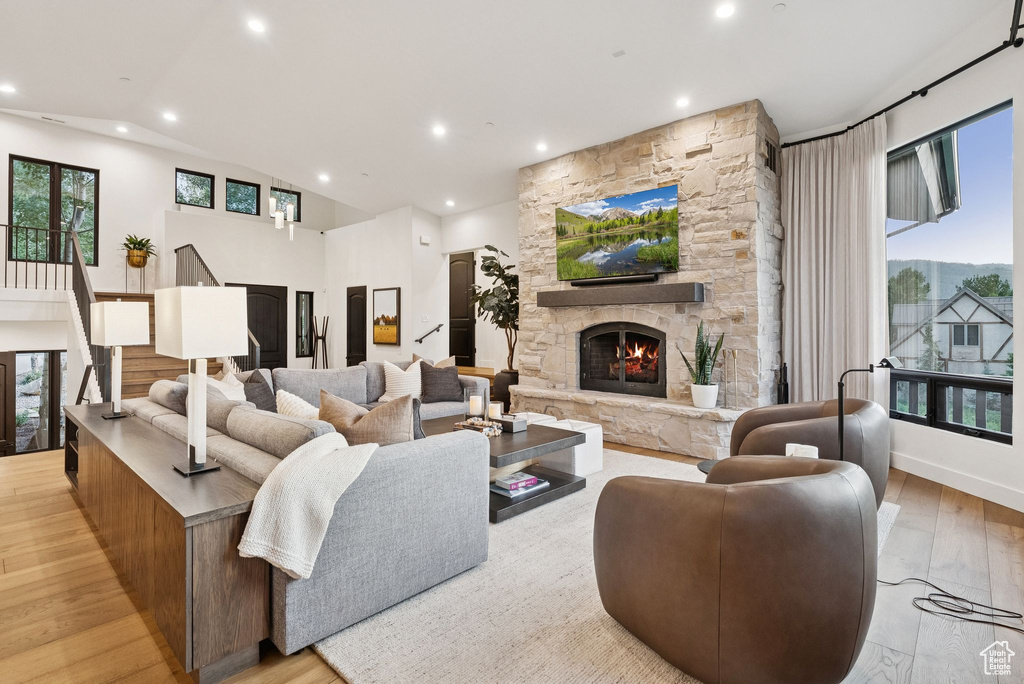 Living room with a stone fireplace, recessed lighting, wood finished floors, healthy amount of natural light, and lofted ceiling