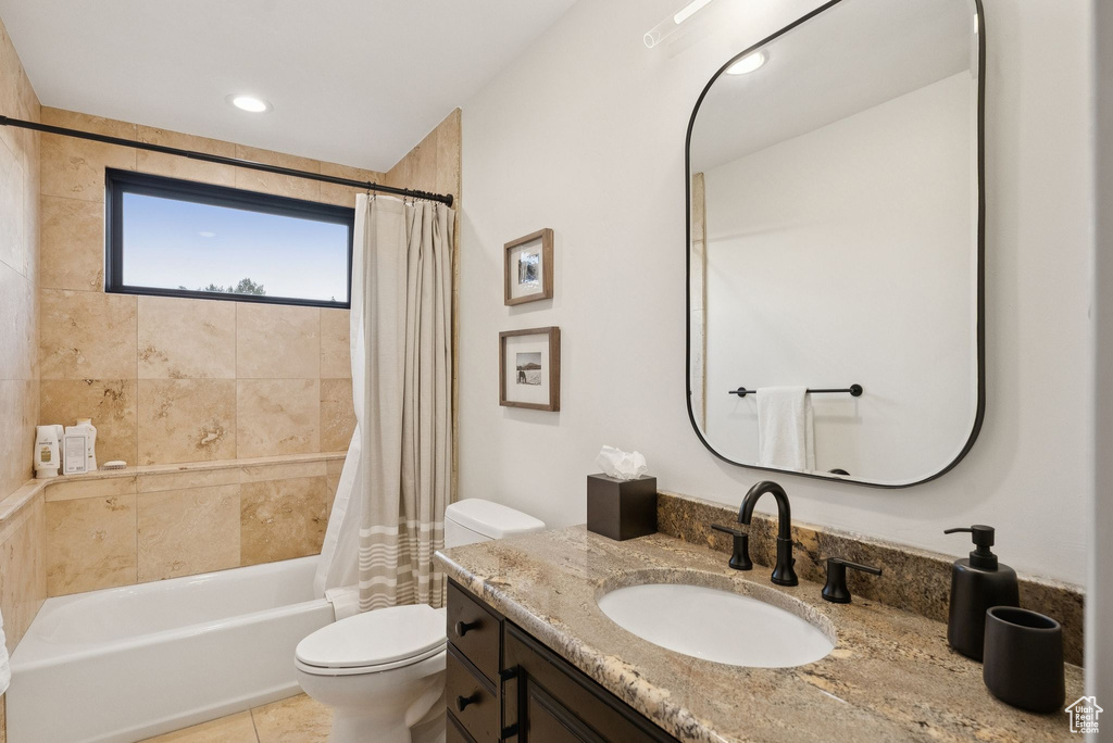 Full bathroom featuring vanity, shower / bath combo with shower curtain, and tile patterned flooring