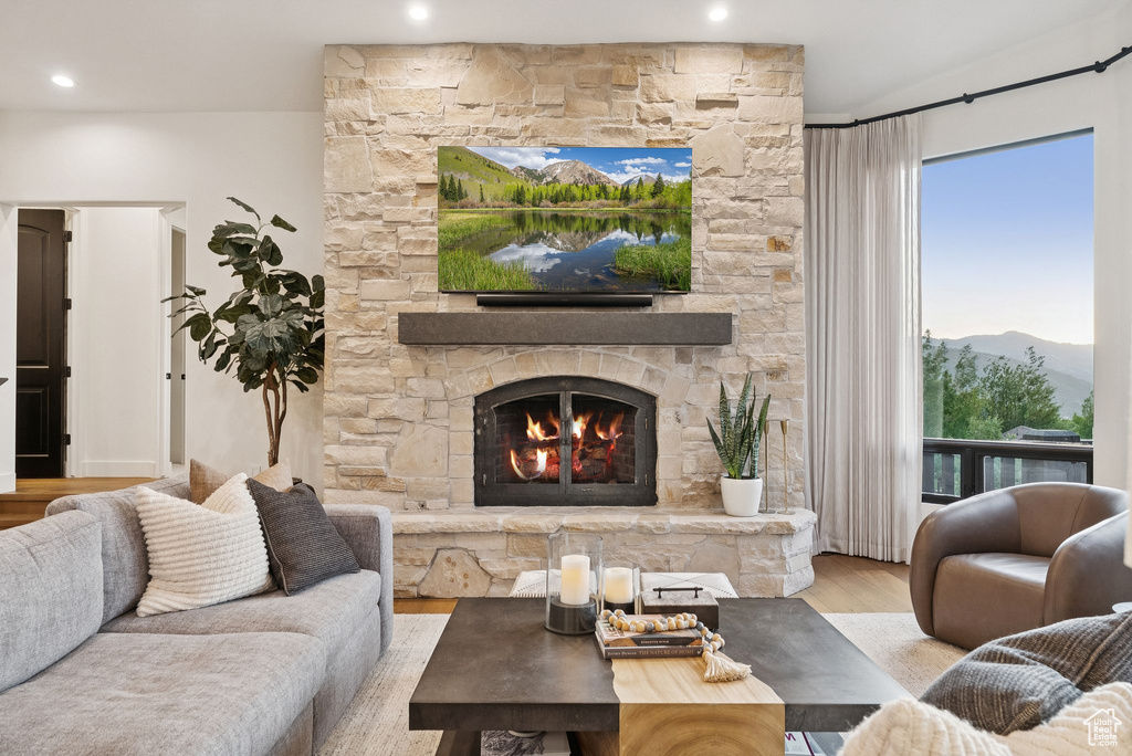 Living area with wood finished floors, a stone fireplace, and recessed lighting