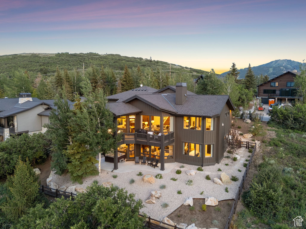 Rear view of property featuring a patio area, a chimney, roof with shingles, and a mountain view
