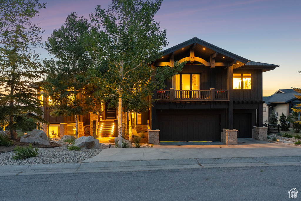 View of front of home with board and batten siding, driveway, stairs, and stone siding