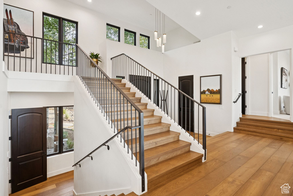 Stairway with hardwood / wood-style flooring, a high ceiling, and recessed lighting