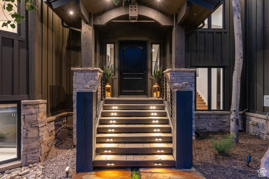 View of exterior entry featuring board and batten siding and stone siding