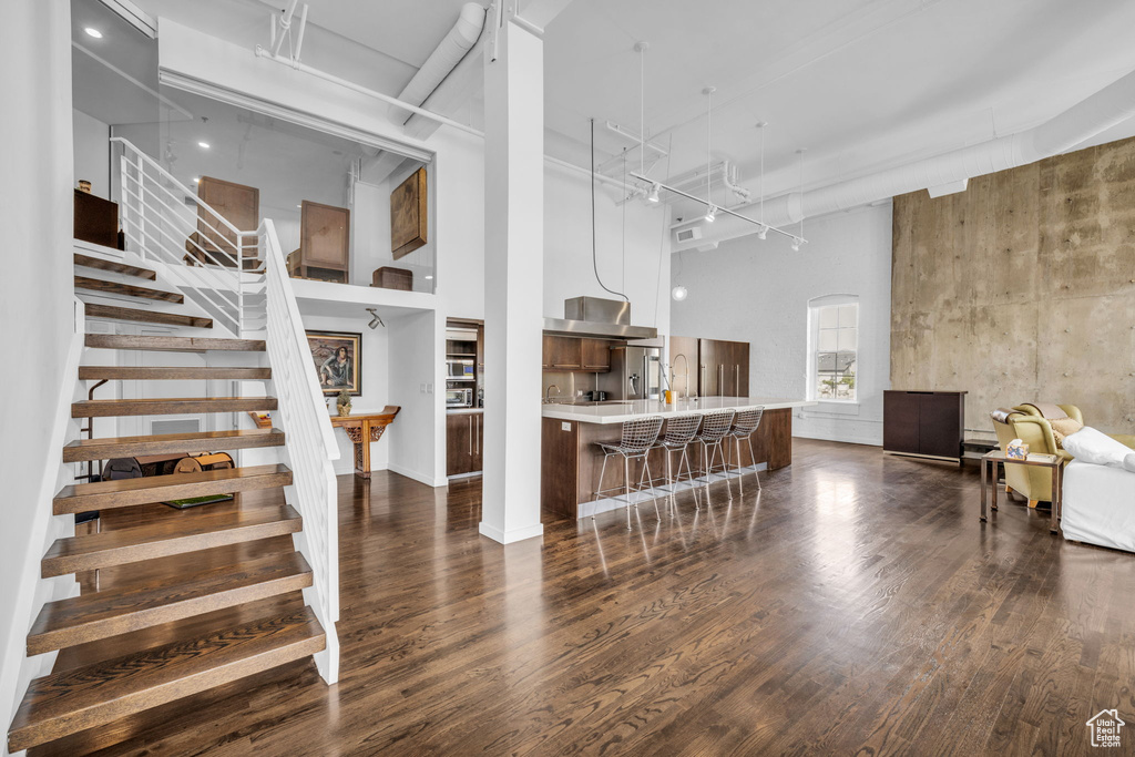 Kitchen with a towering ceiling, modern cabinets, light countertops, a kitchen bar, and freestanding refrigerator
