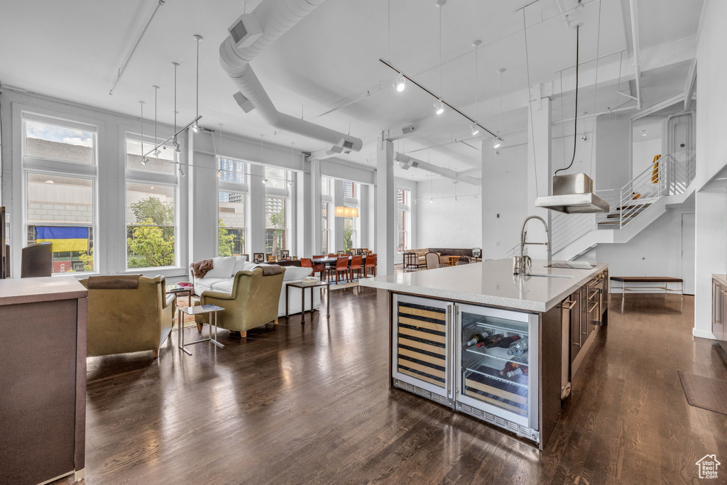 Kitchen featuring wine cooler, open floor plan, light countertops, and an island with sink