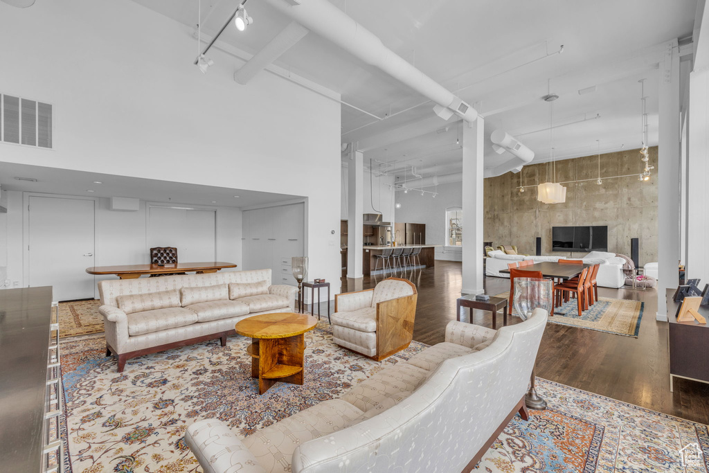 Living area featuring a high ceiling, wood finished floors, and track lighting