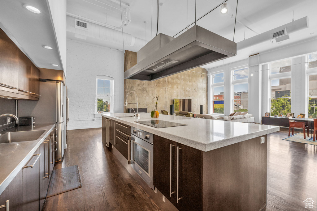 Kitchen with stainless steel oven, dark wood-style flooring, wall chimney exhaust hood, and modern cabinets