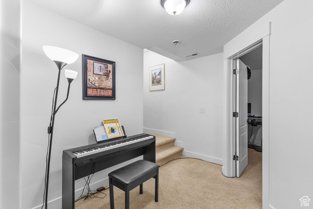 Hall featuring carpet flooring, stairs, and a textured ceiling