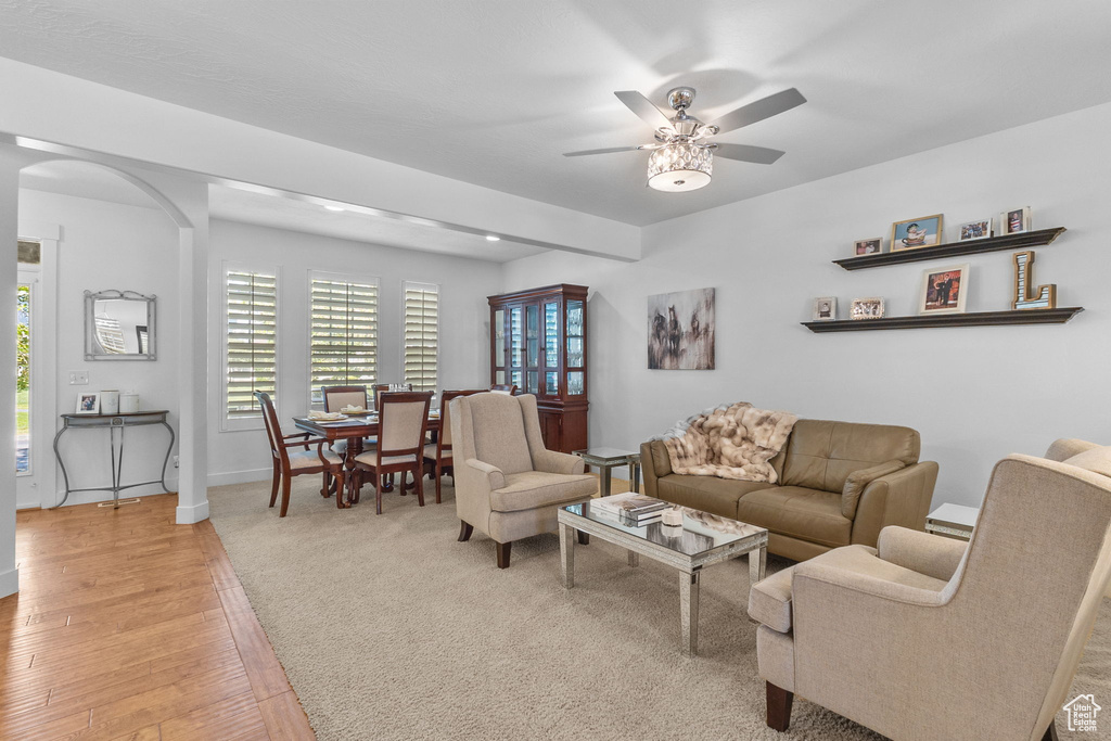 Living room with arched walkways, plenty of natural light, ceiling fan, and light wood-style flooring