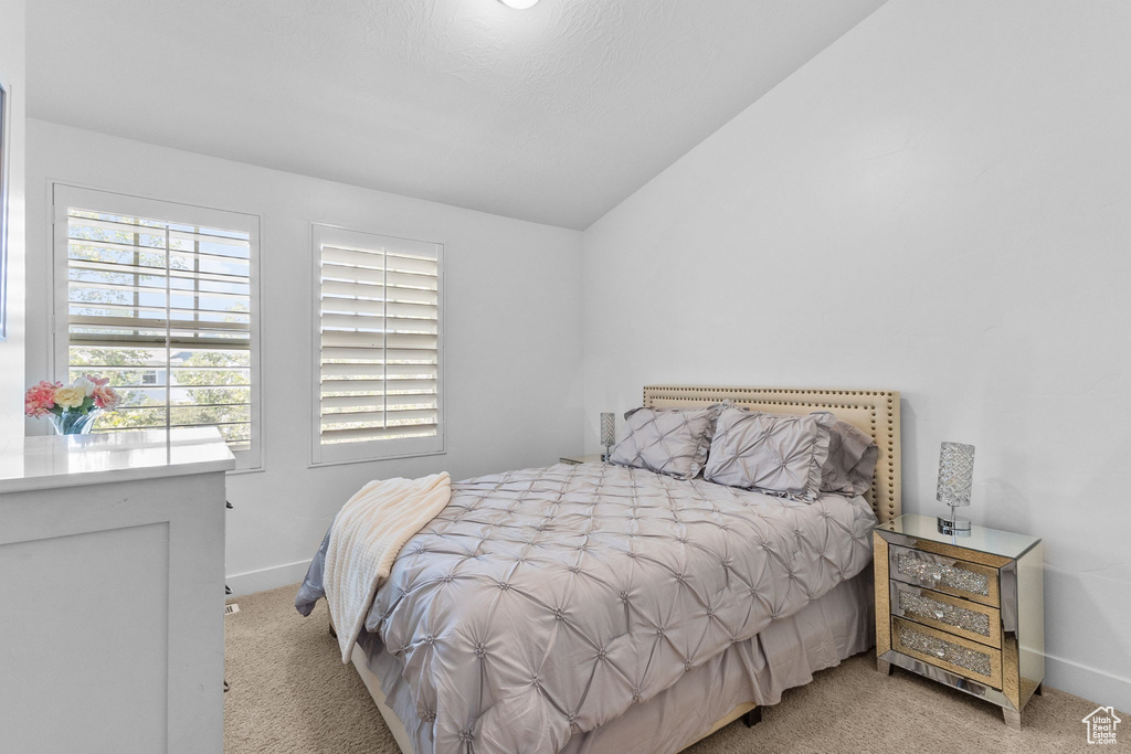Bedroom with light carpet and vaulted ceiling