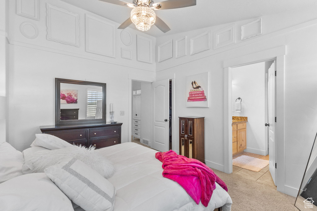 Bedroom with light carpet, ensuite bath, and a ceiling fan