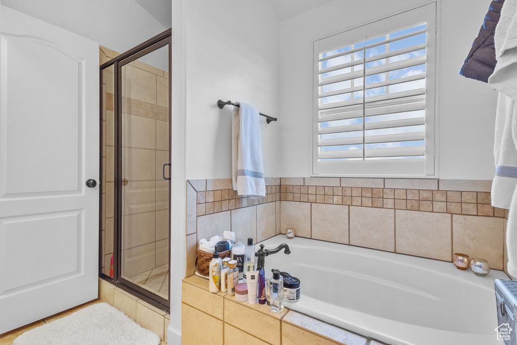 Bathroom featuring a garden tub and a shower stall