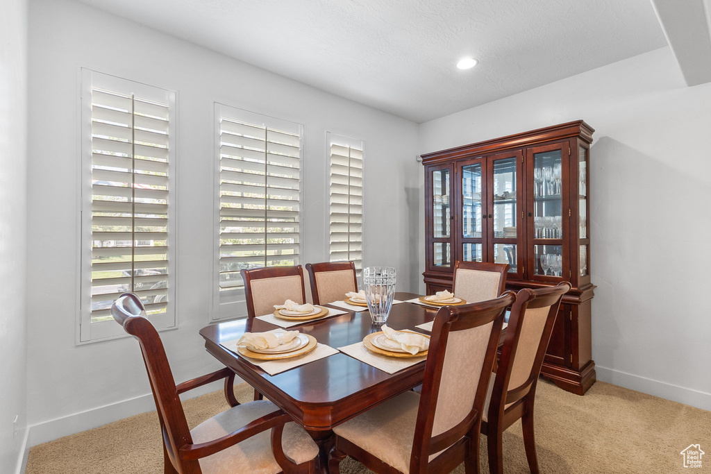 Dining area with light colored carpet and recessed lighting