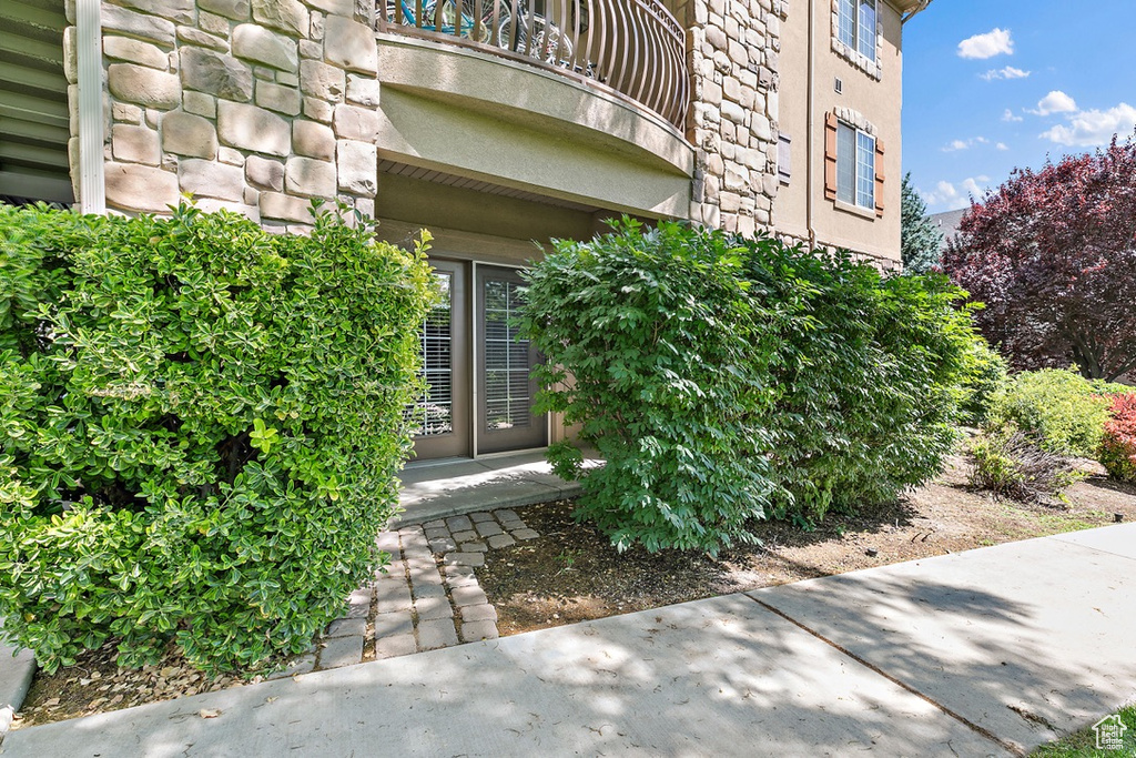 View of exterior entry featuring a balcony, stone siding, and stucco siding