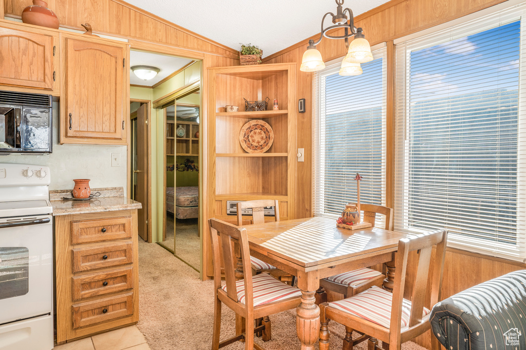 Dining space with vaulted ceiling, wooden walls, light tile patterned flooring, built in features, and light carpet