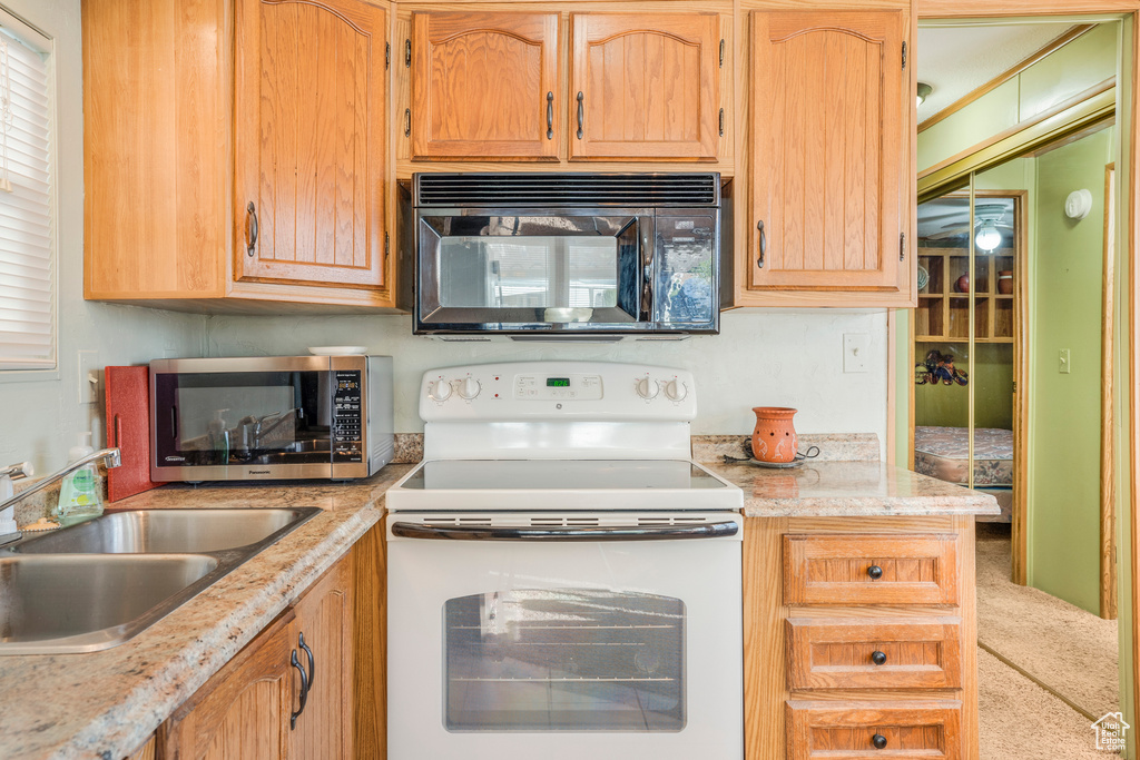 Kitchen featuring black microwave, white range with electric cooktop, stainless steel microwave, and carpet