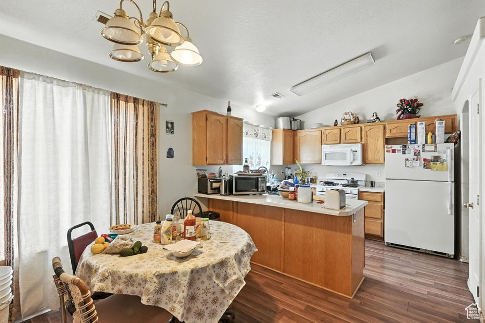 Kitchen with white appliances, vaulted ceiling, a peninsula, a chandelier, and light countertops