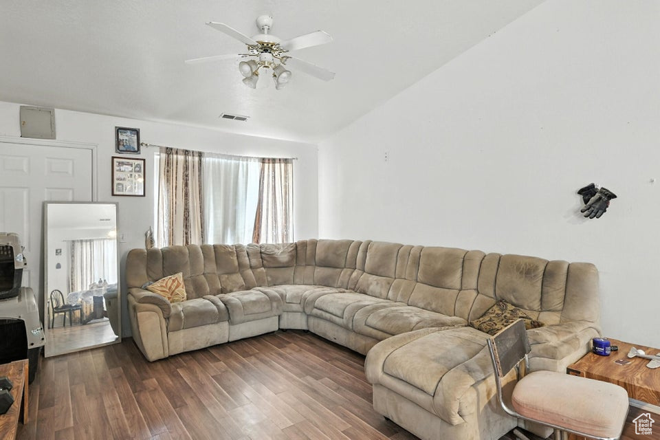 Living room featuring ceiling fan, wood finished floors, and vaulted ceiling