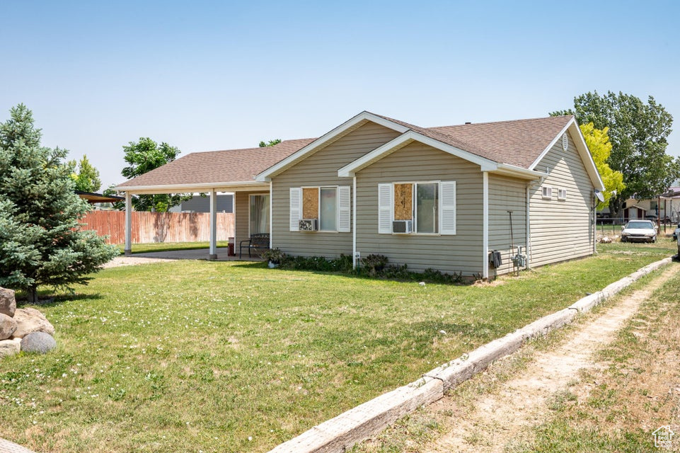 Single story home featuring a shingled roof, a carport, and cooling unit