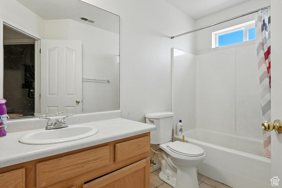 Full bath with vanity, shower / bath combo with shower curtain, and tile patterned floors