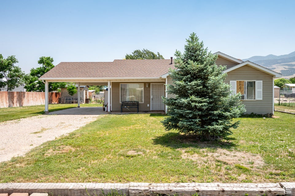 View of front of house featuring gravel driveway, a carport, and a mountain view