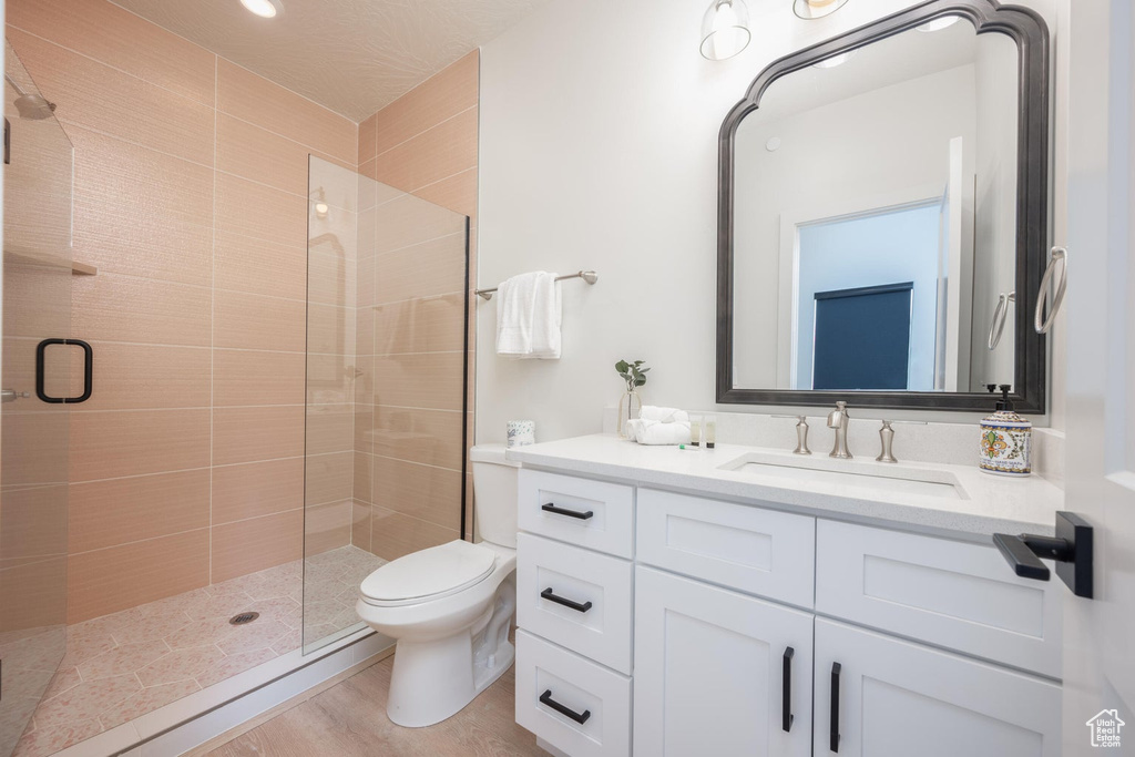 Bathroom featuring a stall shower, vanity, and wood finished floors