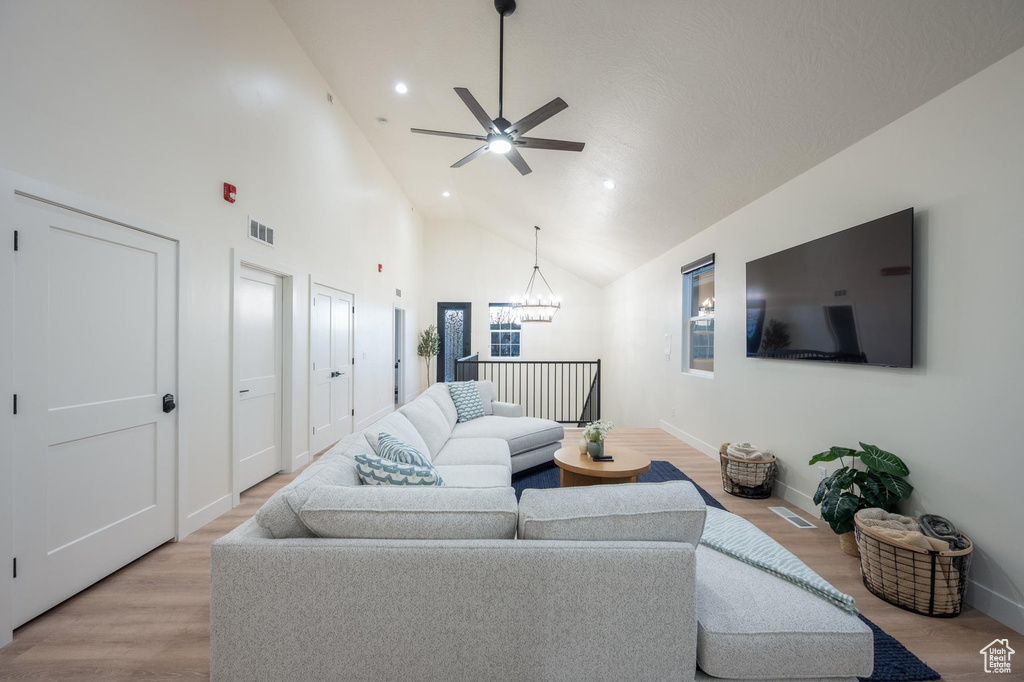 Living area featuring light wood-style floors, a ceiling fan, high vaulted ceiling, a chandelier, and recessed lighting