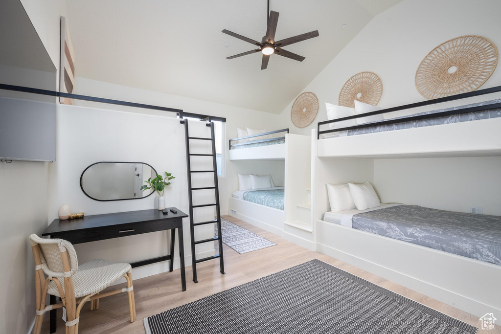 Bedroom with wood finished floors, a barn door, and high vaulted ceiling